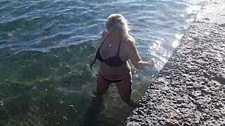 Milf plays with her big tits on the public beach