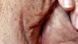 A mature woman plays with her pussy up close, talking dirty in a sexy voice