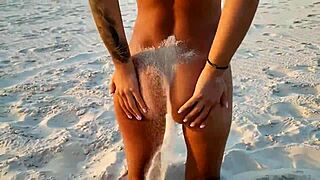 naked monika fox poses on the beach, sprinkling sand while showing her shaved pussy and big tits freely.